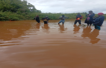 EarthLungs field team crossing floodwater on the way to a restoration site